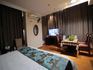 a hotel room with a bed and a table and a television at GreenTree Inn JiangSu WuXi YangJian XiHu Road Express Hotel in Wuxi +53 photos