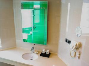 a bathroom with a sink and a green mirror at GreenTree Inn HuaiAn Huaiyin Area The Yangtze River East Road Express Hotel in Huai'an