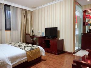 a hotel room with a bed and a flat screen tv at GreenTree Alliance Jiangsu Wuxi Yixing jinsanjiao Bus Station Hotel in Yixing