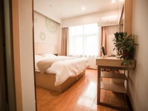 une chambre avec un lit, un bureau et un miroir dans l'établissement GreenTree Inn Heze Yucheng County Dongcheng International Business Hotel, à Yuncheng