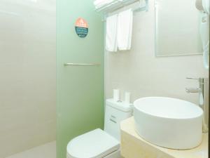 a white bathroom with a toilet and a sink at Shell Jiaxing Jiashan Shenyou Road Hotel in Jiaxing