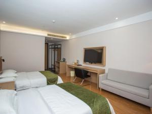 Habitación de hotel con 2 camas, escritorio y TV. en GreenTree Inn Lu'an Kaihong Plaza Express Hotel, en Lu'an