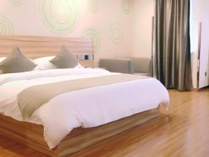 a bedroom with a large bed with white sheets at GreenTree Inn Suzhou Dangshan Yanxi Road Hotel in Dangshan