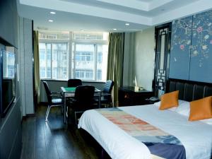 安慶市にあるShell Anqing City Yingjiang District Renmin Road Pedestrian Street Hotelのベッド、テーブル、椅子が備わるホテルルームです。