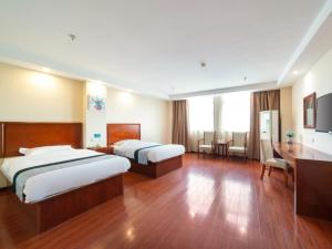 a hotel room with two beds and a desk at GreenTree Inn Jiangsu Suzhou Shengze Bus Station Business Hotel in Suzhou