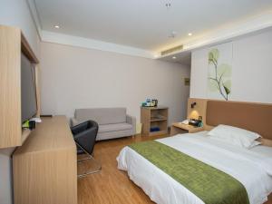 a bedroom with a bed and a desk with a television at GreenTree Inn Lu'an Kaihong Plaza Express Hotel in Lu'an