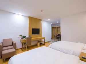 a hotel room with two beds and a desk and a television at GreenTree Inn Anshun Xihang Road Business Hotel in Anshun