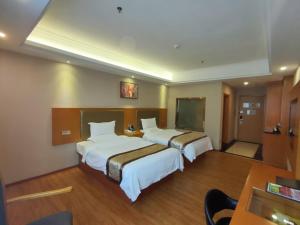 a hotel room with two beds and a table at GreenTree Inn ShanTou HaoJiang DaHao Business Hotel in Shantou