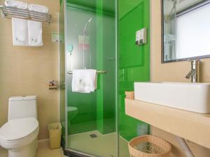 a green bathroom with a toilet and a sink at Vatica ShanDong RiZhao YanZhou Road JinHai Road Hotel in Rizhao