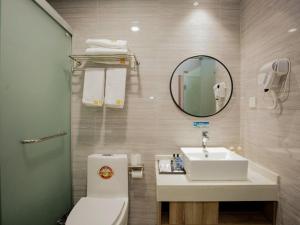 a bathroom with a toilet and a sink and a mirror at Shell Hefei Changjiang West Road Nangang Subway Station Hotel in Hefei