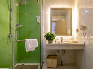 a green bathroom with a shower and a sink at GreenTree Inn Changzhou Zouqu Town Tai fu Times Square Zhenzhong Road Express Hotel in Changzhou