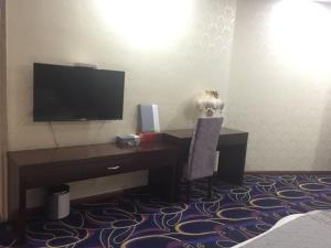 a room with a desk with a television and a chair at GreenTree Alliance Bengbu Railway Station Hotel in Bengbu