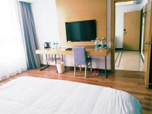a bedroom with a desk with a television and a bed at Vatica Fuyang Linquan County Tenghui International City Hotel in Fuyang
