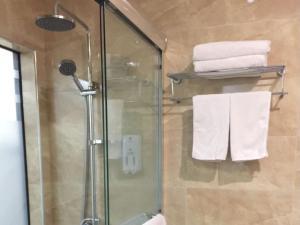 a bathroom with a glass shower stall with towels at GreenTree Alliance Bengbu Railway Station Hotel in Bengbu