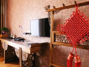 a room with a table and a television on a wall at Shell Jinzhong Pingyao Ancient City East Gate Hotel in Pingyao