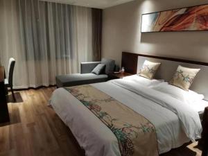 a hotel room with a large bed and a couch at Shell Fuyang City South Bus Station Hotel in Fuyang