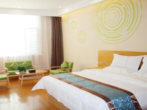 a hotel room with a large bed and chairs at GreenTree Inn Yulin South Changcheng Road Business Hotel in Yulin
