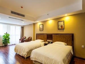 two beds in a hotel room with yellow walls at GreenTree Inn Chengdu high-tech Development West Zone Shidai Tian Street Express Hotel in Chengdu