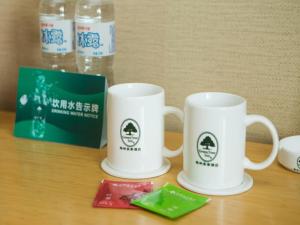 duas canecas de café brancas em cima de uma mesa em GreenTree Inn Shandong Linyi Bus Station Express Hotel em Linyi