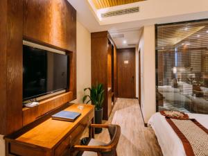 a bedroom with a desk with a television and a bed at GreenTree Eastern Changzhou Liyang CityTianmu Lake Four Seasons Hotel in Liyang