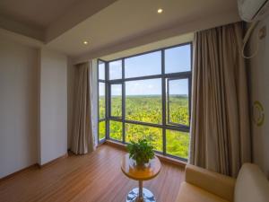 um quarto com uma grande janela e uma mesa com uma planta em GreenTree Inn Qionghai Boao Railway Station Business Hotel em Qionghai