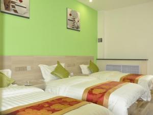 three beds in a room with green walls at Shell Tianshui Taian County Bus Station Hotel in Tianshui
