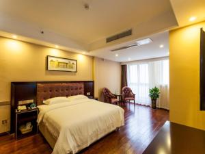 um quarto com uma cama grande, uma mesa e cadeiras em GreenTree Inn Chengdu high-tech Development West Zone Shidai Tian Street Express Hotel em Chengdu