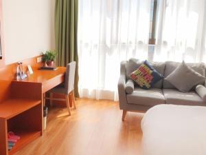 - un salon avec un canapé et un bureau dans l'établissement Vatica Fuyang Linquan County Tenghui International City Hotel, à Fuyang