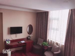 YanzhouにあるGreenTree Inn ShanDong JiNing Chongzhou Train Statiom Beishuncheng Street Express Hotelのデスクとテレビが備わるホテルルームです。