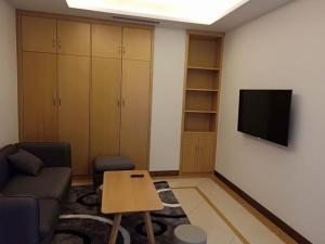 uma sala de estar com um sofá e uma televisão na parede em GreenTree Inn Tangshan Road North District Xishan Road Business Hotel em Tangshan