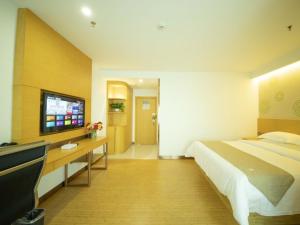 a bedroom with a bed and a desk and a television at GreenTree Inn Handan City Wu'an City Plaza Business Hotel in Handan
