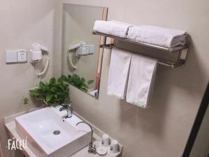 W łazience znajduje się umywalka, lustro i ręczniki. w obiekcie GreenTree Inn ShanDong JiNing Chongzhou Train Statiom Beishuncheng Street Express Hotel w mieście Yanzhou