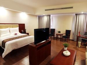 a hotel room with a bed and a flat screen tv at GreenTree Inn GuangDong Jieyang Konggang District Wangjiang North Road Business Hotel in Jieyang +26 photos