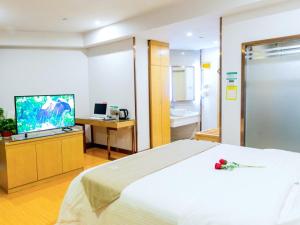 a bedroom with a large bed and a television at GreenTree Inn Anhui Fuyang Yingshang Yingyang Road Suzhou Manor Business Hotel in Jingzhuang