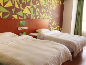 - une chambre avec 2 lits et un mur avec des triangles dans l'établissement Vatica Fuyang Linquan County Tenghui International City Hotel, à Fuyang