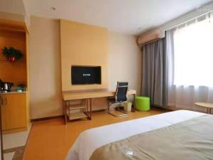 a bedroom with a bed and a desk with a television at GreenTree Inn Langfang Bazhou City Tangeerli Town Spa Business Hotel in Langfang