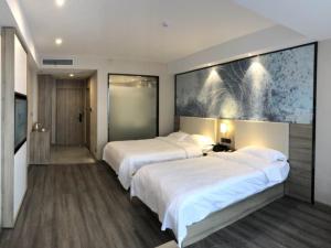 a hotel room with two beds and a flat screen tv at GreenTree Eastern Huai'an Railway Station Mandu Plaza Hotel in Huai'an