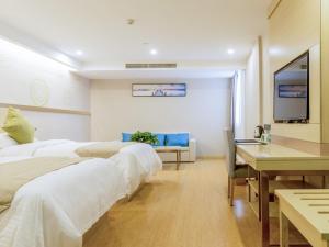 a hotel room with two beds and a desk and a tv at GreenTree Inn Wuxi Yixing High-speed Railway Station Dingshu Town Tongshu Road Express Hotel in Wuxi