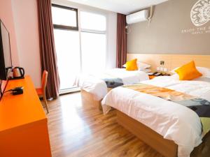 a hotel room with two beds and a window at Shell Zhangjiakou City Qiaodong District Ginza Hotel in Zhangjiakou