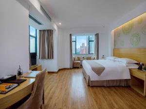 a hotel room with a large bed and a desk at GreenTree Inn Zhongshan West District Fuhua Road Hotel in Zhongshan