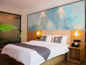 a bedroom with a white bed with a large painting on the wall at GreenTree Eastern Huai'an Railway Station Mandu Plaza Hotel in Huai'an