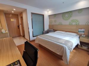 a bedroom with a large bed and a desk at GreenTree Inn Bozhou Chunyu Motor City Express Hotel in Bozhou