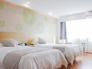 a bedroom with three beds with white sheets and a window at GreenTree Inn HuaiAn Huaiyin Area The Yangtze River East Road Express Hotel in Huai'an