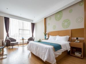 a hotel room with a large bed and a chair at GreenTree Inn Wuxi Jiangyin City Renmin East Road Liangchen Square Business Hotel in Jiangyin