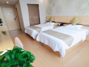 a hotel room with two beds and a plant at GreenTree Inn Huainan Shannan New District Erzhong Business Hotel in Sanhe