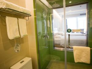 a green bathroom with a shower and a toilet at GreenTree Inn Suzhou Yongqiao District Fuxiao Avenue Hotel in Suzhou