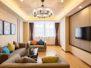 a living room with a couch and a flat screen tv at GreenTree Inn Wuxi Jiangyin City Renmin East Road Liangchen Square Business Hotel in Jiangyin