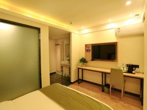 a hotel room with a desk and a television at GreenTree Inn Anlong County Zhaodi Hotel in Xingyi