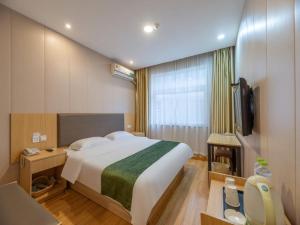 een hotelkamer met een groot bed en een televisie bij GreenTree Inn Shandong Jining Railway Station Express Hotel in Jining