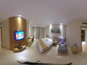ChangshuにあるGreenTree Inn JiangSu SuZhou ChangShu South HaiYu Road Walking Street Business Hotelのベッドとテレビが備わる広いホテルルームです。